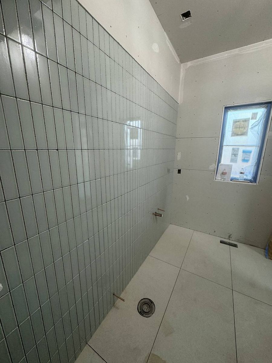 Sage green vertical stacked wall tile running the length of a walk-in shower with a linear floor drain